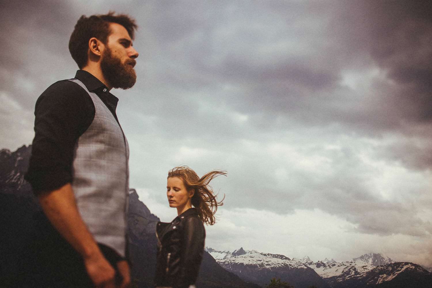 Husband and wife standing in front of the ice capped mountains in the French Alps while celebrating their anniversary with Magic the Photographer